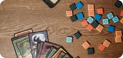 Speelkaarten en tegels met patronen van een bordspel op een houten tafel, gezien van bovenaf